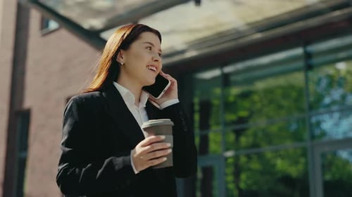 Happy Caucasian Businesswoman in Formal Suit Going Near the Business Center Speaking on the Phone