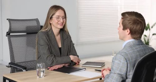 Lächelnder Personalvermittler und Kandidat beim Vorstellungsgespräch am Tisch im Büro