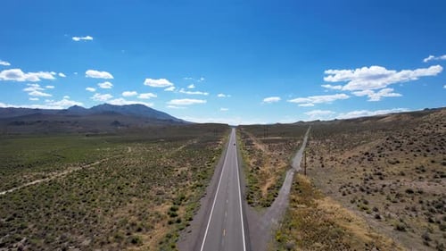 Long straight Open road in Nevada Desert with two cars passing each other - Aerial ascending