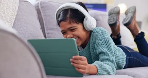 Girl Lying on Couch Watching Tablet with Headphones