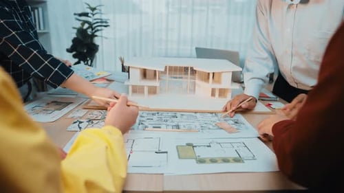 Team of Architects Collaborating on Construction Project with Blueprints and Models at Office Table