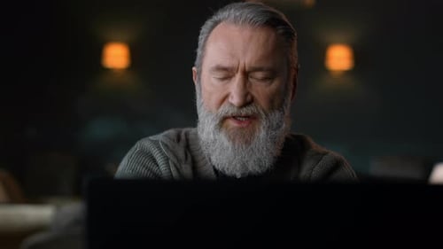 Senior Man Looking at Laptop Screen Indoors
