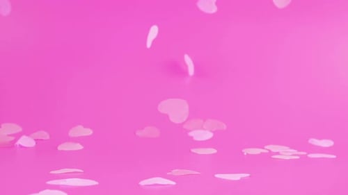 Flying confetti on a pink background. Slow motion.