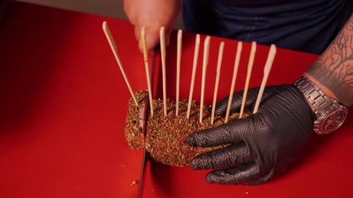 Chef Cutting Seasoned Meat on Red Cutting Board