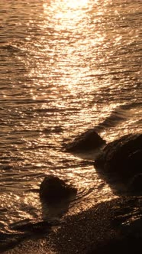 Golden Waves Lap Rocky Shoreline at Sunset
