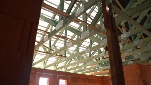Interior view of new house under construction with brick walls and roof trusses and battens