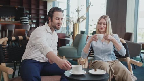 Happy Attractive Young Couple Sitting Talking Drinking Coffee Smiling Man and Woman in a Modern Cafe