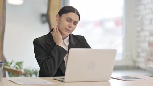 Businesswoman Works on Laptop and Stretches Neck