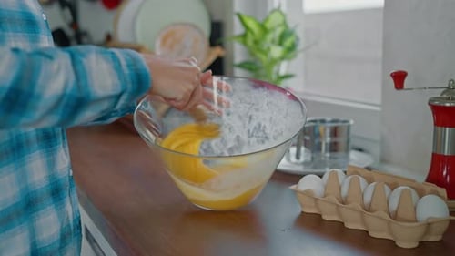 Frau mit Schneebesen beim Eiermixen in einer Glasschale