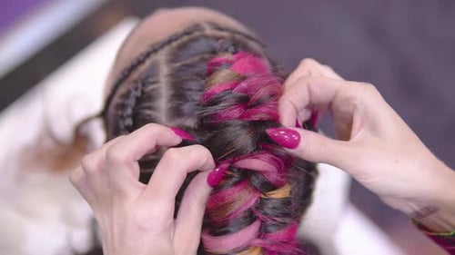 close up of hands tiding up colourful braided hair very unique extravagant professional hairstyle sl