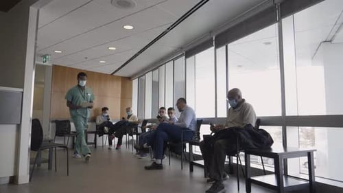 Male Nurse and Patients in Protective Face Masks in Clinic Waiting Room 10 Seconds or Greater