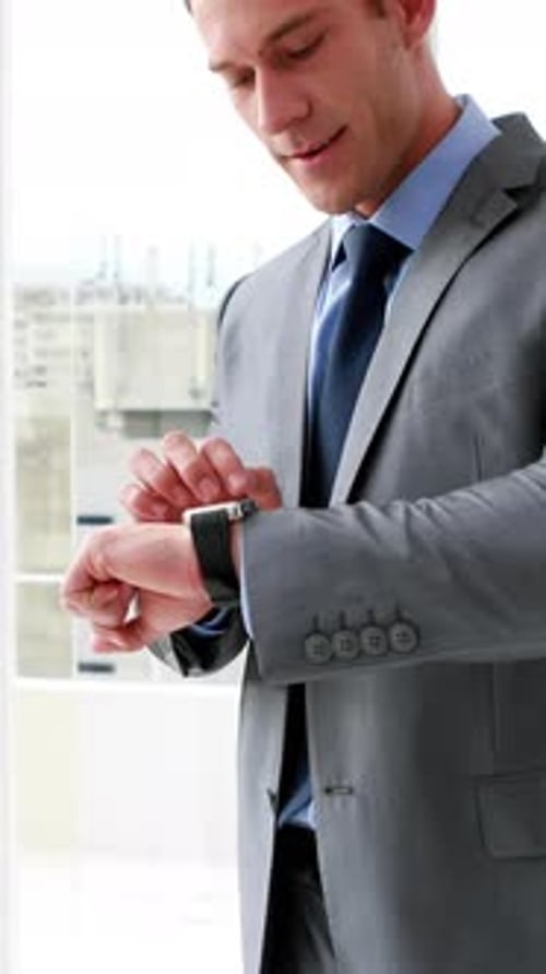Vertical video of a young Caucasian businessman checks his watch in an office, with copy space