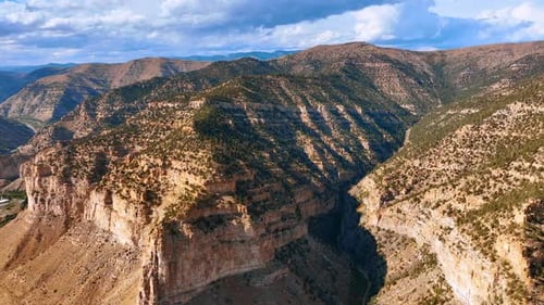 Drone view of rugged red rock formations and green patches along the canyon