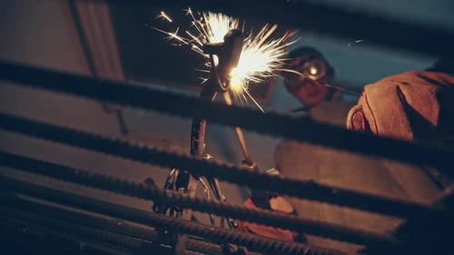 Metalworker in Safety Gear Working with an Acetylene Torch Viewed From Below Through an Open Metal