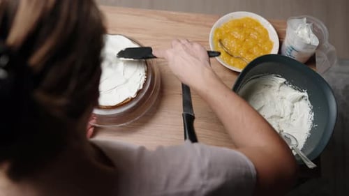 Die Kamera fotografiert von hinten und oben eine Konditorin, während sie den Kuchen zubereitet und verteilt