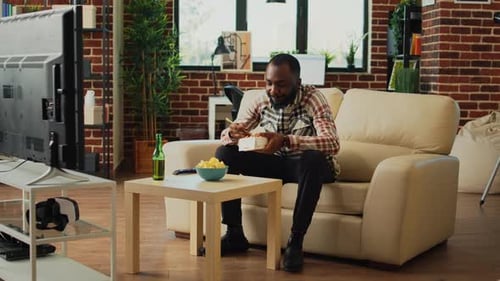 Man Eating Noodles at Home on Couch