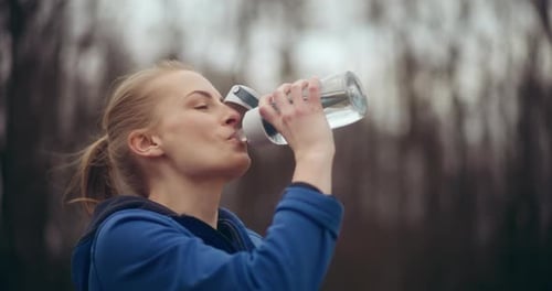 Female Athlete Drinking Water After Workout in Park
