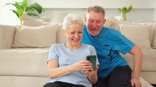 Senior Couple Looking at Smartphone Together Indoors