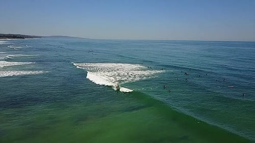 VISTA AÉREA: surfistas en el agua en Encinitas, California, tiro ancho a la izquierda