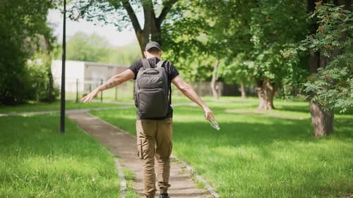 Man Walks Down Path in Park and Celebrates