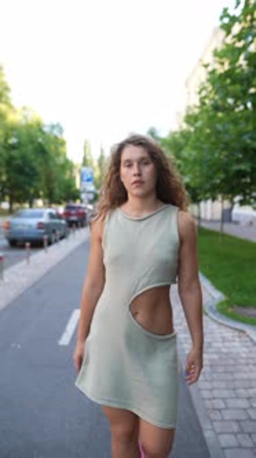 Sporting Summer Attire and Curly Hair a Girl Takes a Casual Walk Through the City
