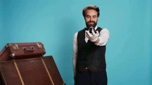 Man Rings Silver Bell Next to Vintage Suitcases