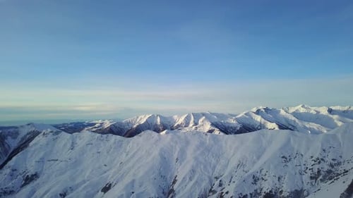 Wide Aerial Panorama of Snowy Mountain Ridge at Ski Resort Village on Sunrise Stunning Mountains