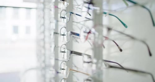 Fashionable corrective eye glasses on a shelf of an optical shop for clients to choose from