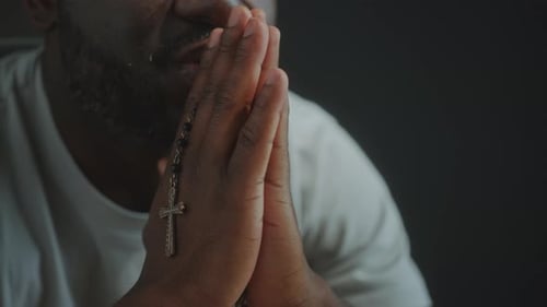 Close Up of Person Praying with Rosary