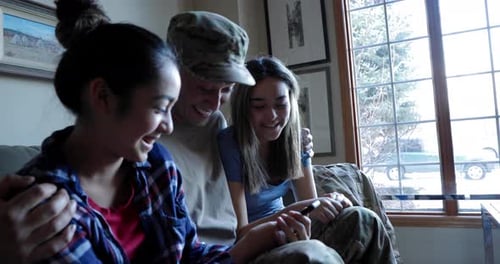 Smiling Family on Sofa Looking at Mobile Phone