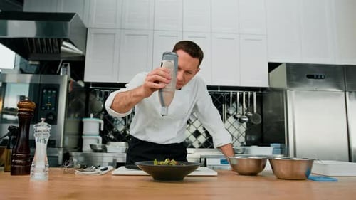 Professional kitchen the chef pours sauce on the salad with pear and cheese mixes the ingredients