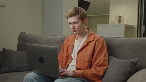 Young Adult Using Laptop on Gray Couch