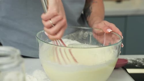 Frau rührt Mehl und Eierteig in einer Schüssel um, um ein Dessert zuzubereiten. Nahaufnahme