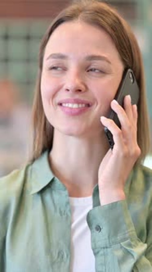 Smiling Young Woman Talking on Smartphone Indoors