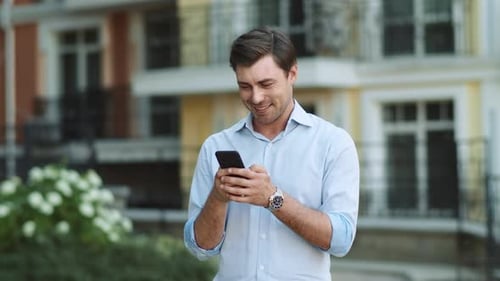 Happy Businessman Using Smartphone at Street. Portrait of Cheerful Business Man Typing