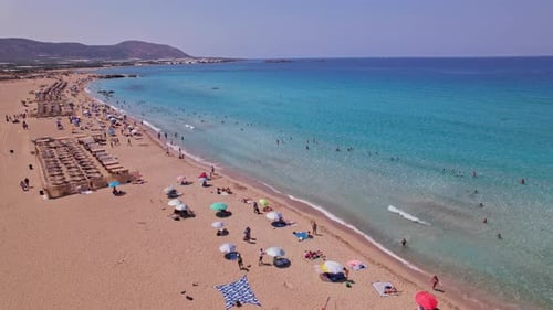 Vibrant beach scene on a sunny day with colorful umbrellas and clear water