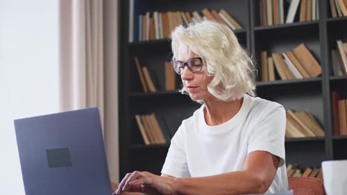 Mature Woman Typing on Laptop at Desk