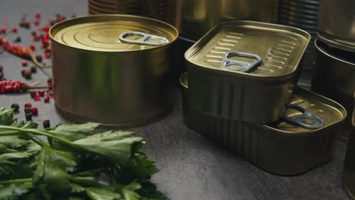 Latas de metal con comida enlatada o paté sobre la mesa, primer plano, latas doradas y plateadas con anillos de tracción enlatadas