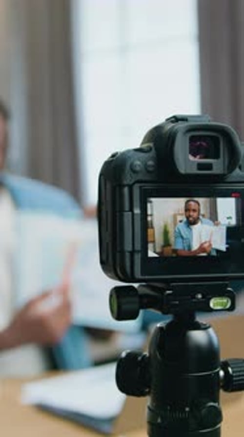Man Records Video Holding Papers Indoors at Desk