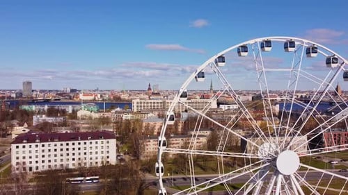 White Ferris Wheel with cityscape of Riga, showcasing recreational attraction in big capital city