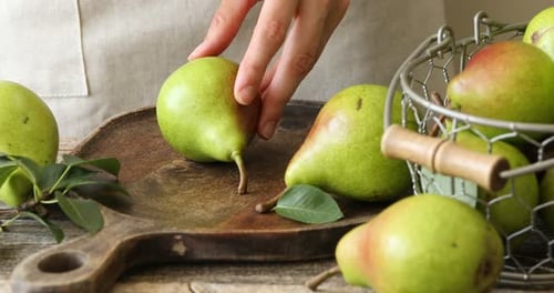 Woman cutting fresh ripe pear at wooden table, closeup