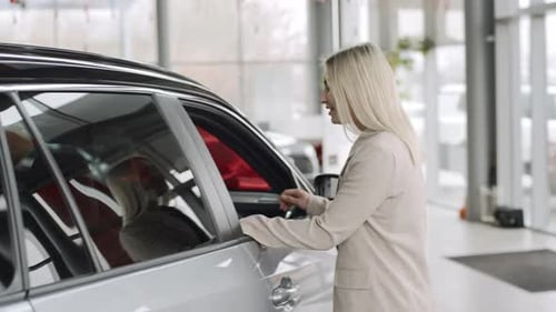 Slow motion of a woman exploring cars in a showroom with the intention to buy or test drive