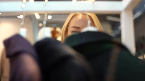 Closeup Face of Pretty Blonde Woman with Charming Smile Plucked Hanger Choosing Clothes in Clothing