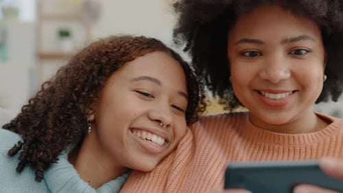 Smiling Women Watching Phone Together Indoors