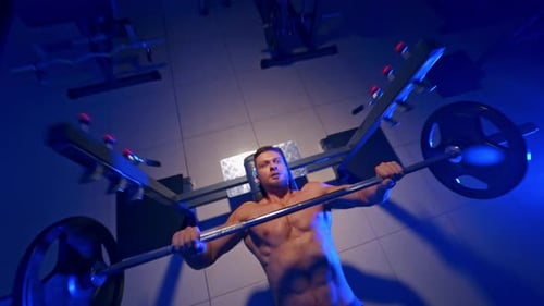 Fit man exercising in gym. Young muscular man with naked torso exercising in gym