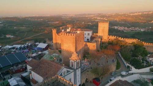 Tours du château surplombant le village avec des toits de tuiles rouges, vue aérienne panoramique