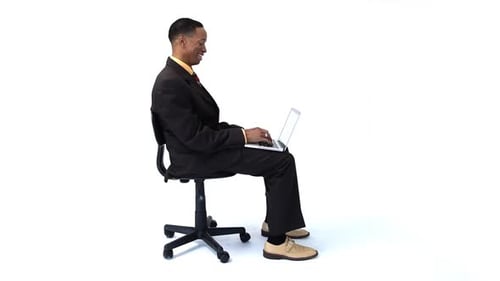 Man in suit sits and types on laptop