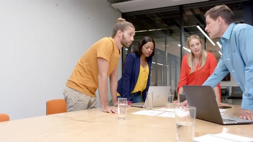 Happy diverse colleagues with laptops in discussion at casual office meeting, slow motion
