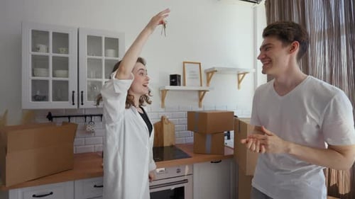 Happy Woman and Man Show Key to New Apartment at Camera