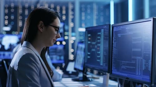 Close-up Footage of Female IT Engineer Working in Monitoring Room. She Works with Multiple Displays